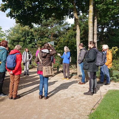 Bild vergr&ouml;&szlig;ern: Anna Zietz, Mitarbeiterin der Schule im Grünen im Park der Gärten mit einer Gruppe beim geführten Rundgang durch den Park