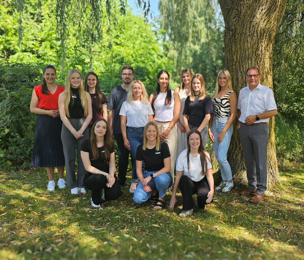 Gruppenfoto der Auszubildenden 2026 beim Landkreis Ammerland in einer grünen Parkanlage unter Bäumen.