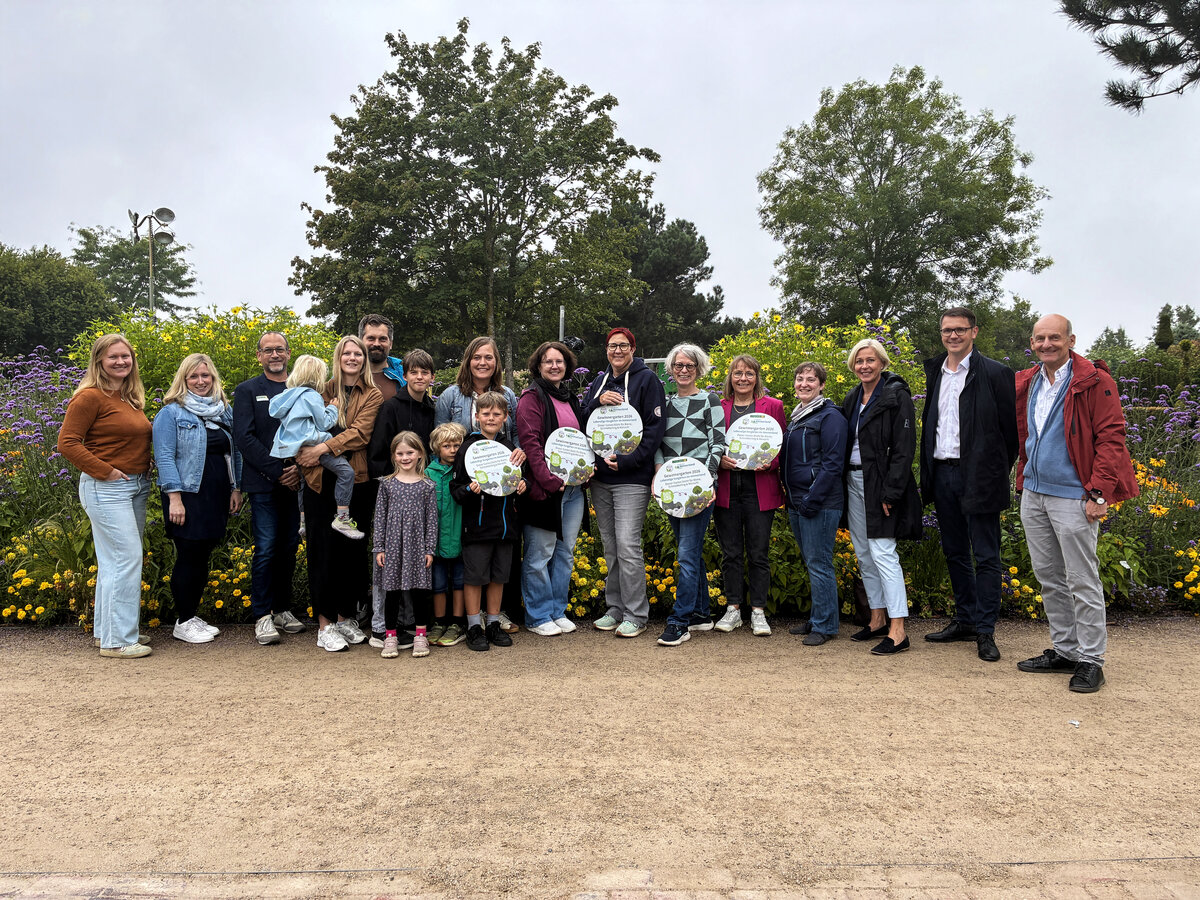 Gewinnerinnen, Initiatoren und Gäste des Vorgartenwettbewerbs stehen im Park der Gärten zusammen; mehrere Personen halten ihre Urkunden.